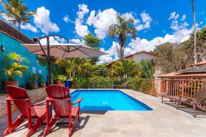 a swimming pool with two chairs and an umbrella at Pousada Casa Zanotto in Pirenópolis