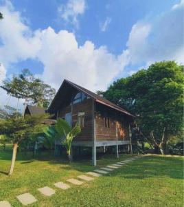 a small wooden house in a field with trees at บ้านวารีชีวา WareeCheewa in Ban Muai