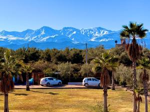 two cars parked in a parking lot with mountains in the background at Maison Dar Zarka in Aghmat