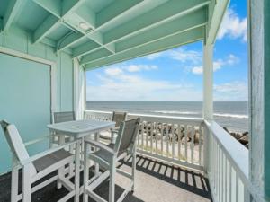 a balcony with a table and chairs and the ocean at A Beach Dream condo in Carolina Beach