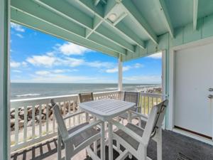 a table and chairs on a balcony with the ocean at A Beach Dream condo in Carolina Beach