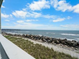 a view of a beach with a fence and the ocean at A Beach Dream condo in Carolina Beach