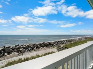 a view of a beach with a fence and the ocean at A Beach Dream condo in Carolina Beach