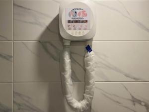 a white phone hanging on a wall in a bathroom at Mora Stay in Busan