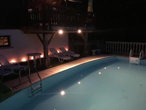 a swimming pool at night with chairs and lights at Poolside Bliss Near Lake in Beaulieu