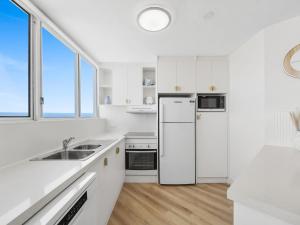 a white kitchen with a refrigerator and a sink at Mandolin Beachfront Resort in Alexandra Headland