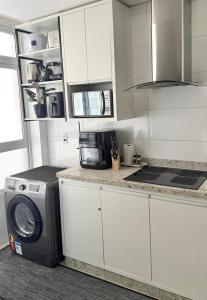 a kitchen with a washing machine and a microwave at Praia da Graciosa Apartamento 2 quartos in Palmas