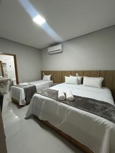 a bedroom with two beds with white sheets at Hotel Almeida in Montes Claros