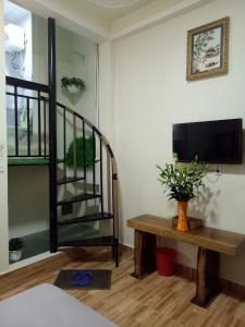 a living room with a table and a tv and stairs at Anh Đào Dalat House in Da Lat