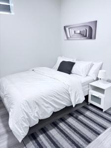a white bedroom with a bed and a mirror at Cozy Home basement suite with private separate entrance in Winnipeg