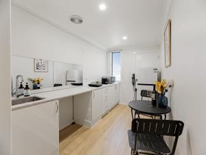a kitchen with white cabinets and a table and chairs at North Ipswich 1BR Pine Studio in Ipswich