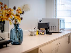 a counter with a vase of flowers and a microwave at North Ipswich 1BR Pine Studio in Ipswich