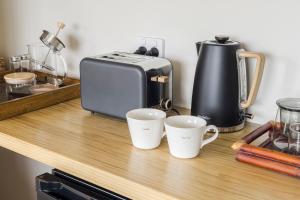 a counter with two coffee cups and a toaster at Puna BnB in Matamata +11 photos