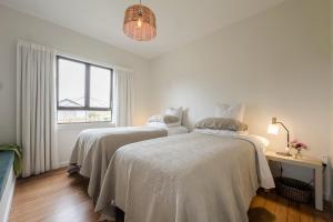 two beds in a white room with a window at Puna BnB in Matamata