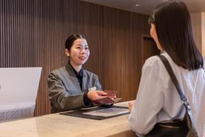 two women sitting at a table with a cell phone at KAMENOI HOTEL Kusatsu Resort in Kusatsu +59 photos