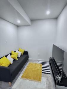 a living room with a black couch and yellow pillows at Cozy Home basement suite with private separate entrance in Winnipeg