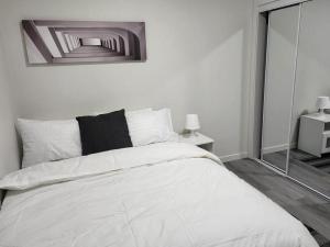 a white bed in a white bedroom with a mirror at Cozy Home basement suite with private separate entrance in Winnipeg +7 photos
