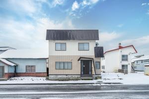 a white house with a black roof on a street at Villas Park Kamifurano in Kami-furano