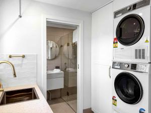 a laundry room with a washer and dryer and a sink at The Winegrower's Cottage in Broke