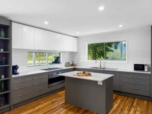 a large kitchen with gray cabinets and white counters at The Winegrower's Cottage in Broke