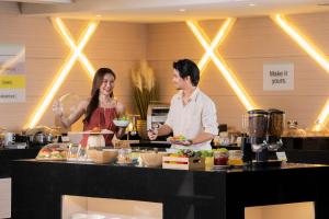 a man and a woman preparing food in a kitchen at Garner Hotel Pattaya Central by IHG in Pattaya