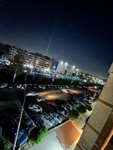 a parking lot with parked cars in a city at night at Comfy 3 Bedrooms Apartment in Cairo Sheraton Airport in Cairo