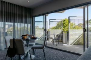 a dining room with a table and chairs and windows at Punthill Essendon in Melbourne