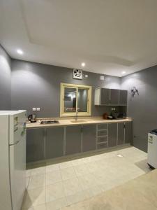 a kitchen with gray cabinets and a white refrigerator at مساكن اركان in Quai