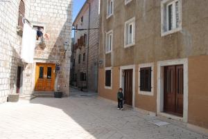 un niño pequeño parado en un callejón al lado de un edificio en Rooms Piazzetta, en Cres