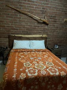 a bed in a bedroom with a brick wall at Hospedaje Samao in Santa María del Oro