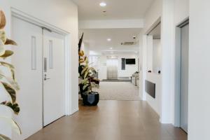 a hallway with white walls and a hallway with plants at Punthill Essendon in Melbourne