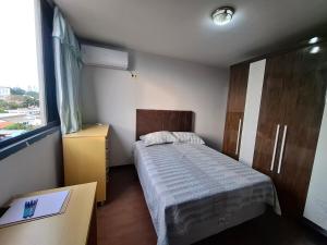 a small bedroom with a bed and a window at Apartmento Moto GP in Goiânia