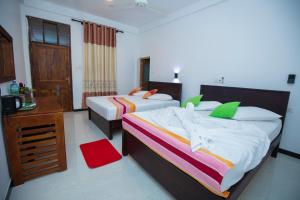 a hotel room with two beds and a desk at River Shade Inn in Tissamaharama