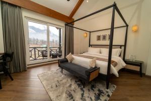 a bedroom with a canopy bed and a large window at Nivasana Manali - A Luxury Boutique Hotel in Manāli
