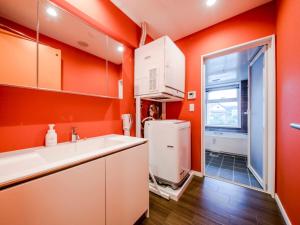a kitchen with orange walls and a white sink at Lieta Nakayama in Nago +12 photos