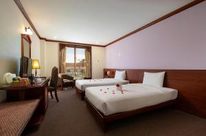 a hotel room with two beds and a desk at TTC Hotel - Da Lat in Da Lat +39 photos