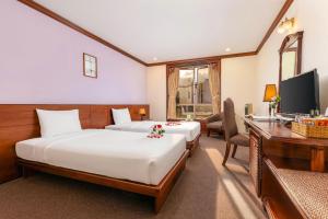 a hotel room with two beds and a desk at TTC Hotel - Da Lat in Da Lat