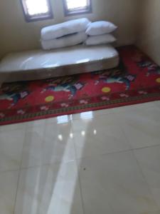 a room with a rug and towels on a table at Musni Guest House in Tarusan