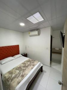 a bedroom with a large bed with a red headboard at Hotel Limaco in Neiva