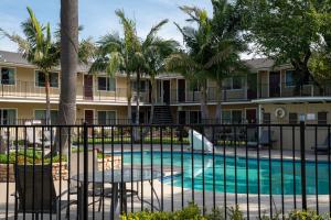 a swimming pool with tables and palm trees in front of a building at Quality Inn & Suites Santa Maria in Santa Maria