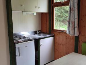 a kitchen with a sink and a stove and a window at Chalet avec terrasse - 6 pers. - API-1-52-2030 in La Tour-dʼAuvergne