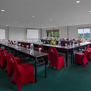 a conference room with tables and red chairs at Grande Padjadjaran Hotel in Kamparganya