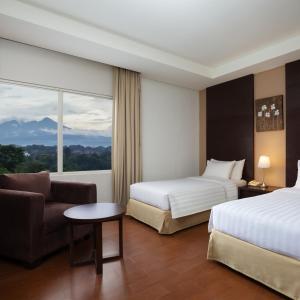 a hotel room with two beds and a couch and a window at Grande Padjadjaran Hotel in Kamparganya +35 photos