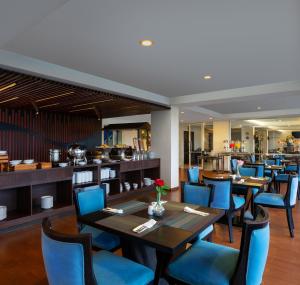 a restaurant with wooden tables and blue chairs at Grande Padjadjaran Hotel in Kamparganya