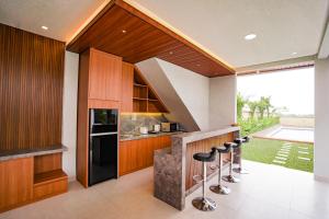 a kitchen with wooden cabinets and a counter with stools at Pondok Uma Jero in Tanah Lot
