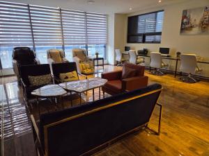 a waiting room with chairs and tables and windows at First Hotel in Guri