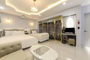 a bedroom with a large white bed and a couch at Hotel Felice Dongchon Amusement park in Daegu