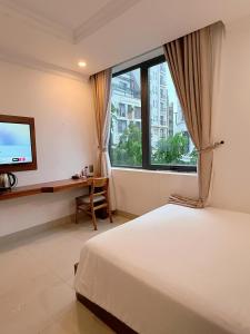 a bedroom with a bed and a desk and a television at Kiwi Beachside Hotel & Cafe Da Nang in Danang +40 photos
