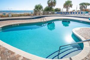 a large swimming pool with blue water and palm trees at Direct Oceanfront Unit Amazing Views with Pools in Myrtle Beach