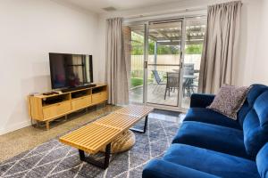 a living room with a blue couch and a tv at Relax at 42 Cape View Resort in Broadwater